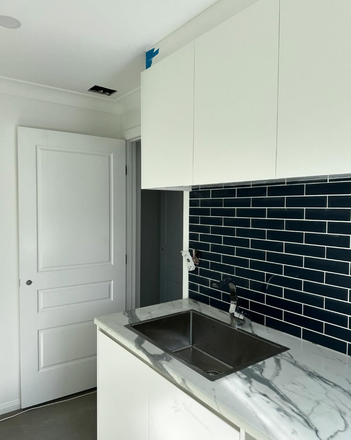 Navy subway tile laundry splashback with marble benchtop