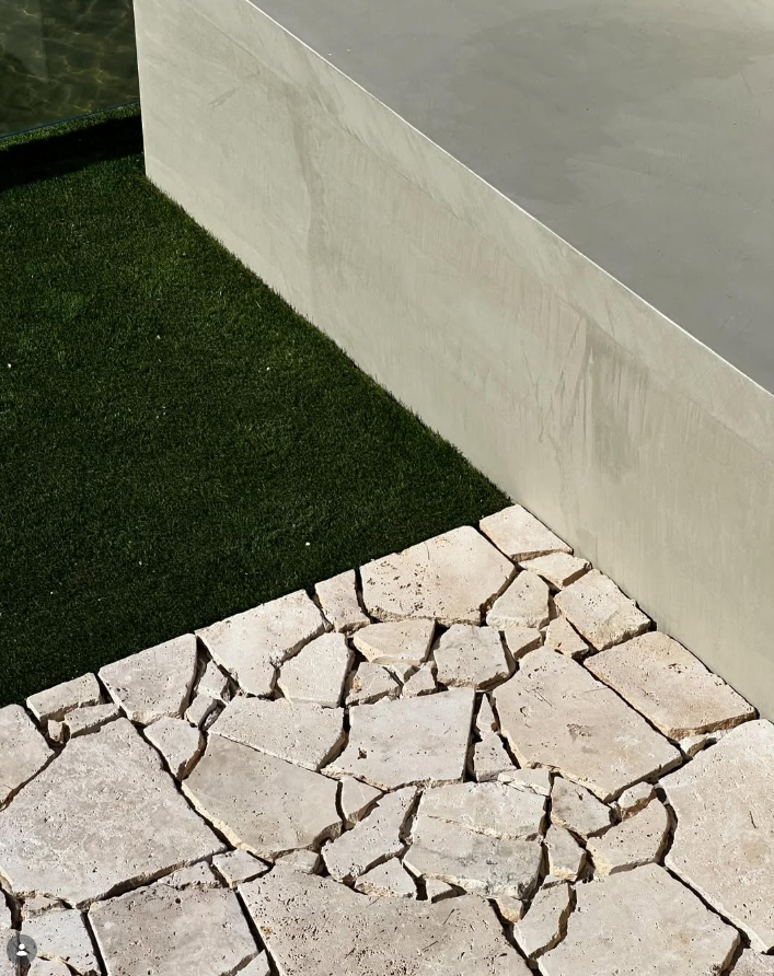 Honed travertine crazy paving beside a rendered pool wall